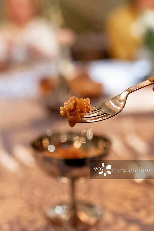 在餐厅里，一位女士用勺子在精致的玻璃杯中品尝奢华的甜点图片素材