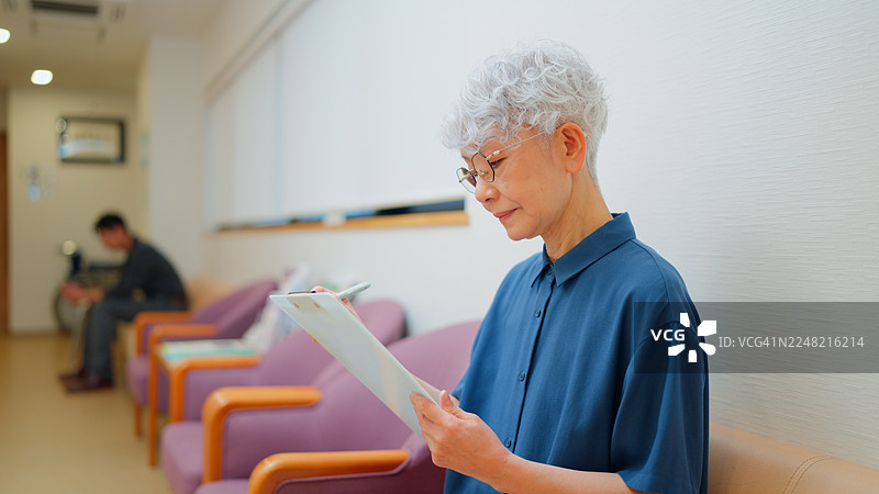 老年女患者在诊所填写医疗问卷图片素材