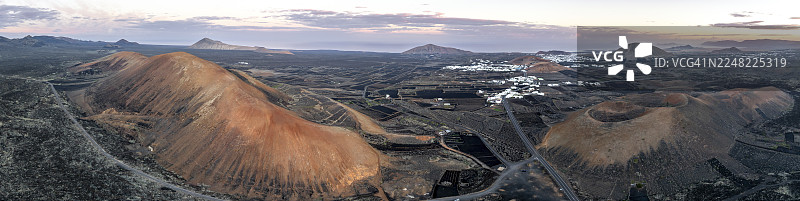 日出时分,兰萨罗特岛洛斯沃尔卡内斯自然公园内,从空中俯瞰塔巴伊巴山和科鲁霍山火山坑的风景如画的火山地貌,西班牙加那利群岛。图片素材
