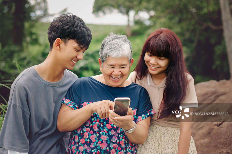 一位年长女性和她的孙辈正在使用手机图片素材