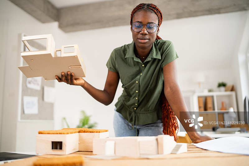 一位严肃的年轻黑人女建筑师正在研究图纸和建筑模型图片素材