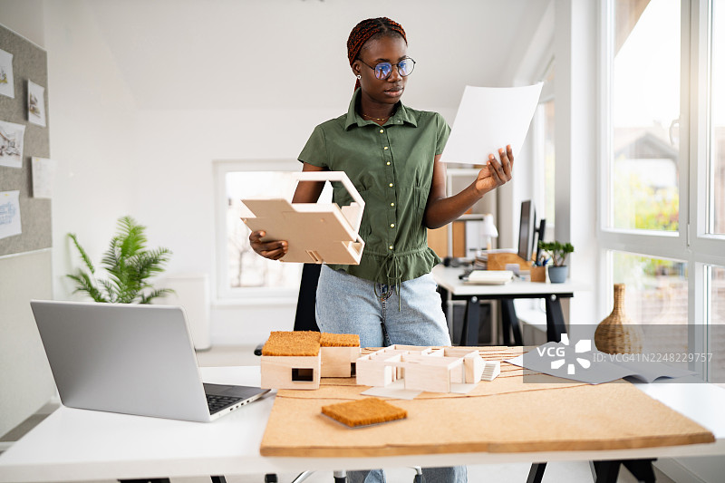 年轻的黑人女建筑师正在对比建筑图纸和模型图片素材