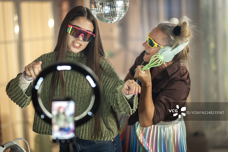 奶奶和孙女在家录制有趣的TikTok挑战，扮演DJ图片素材