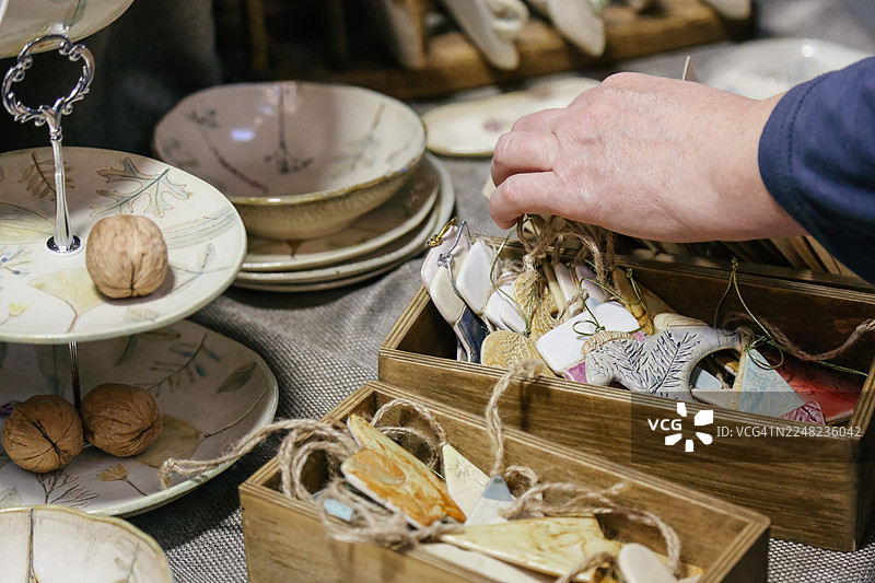 顾客的手在当地圣诞集市上挑选手工制作的新年玩具图片素材