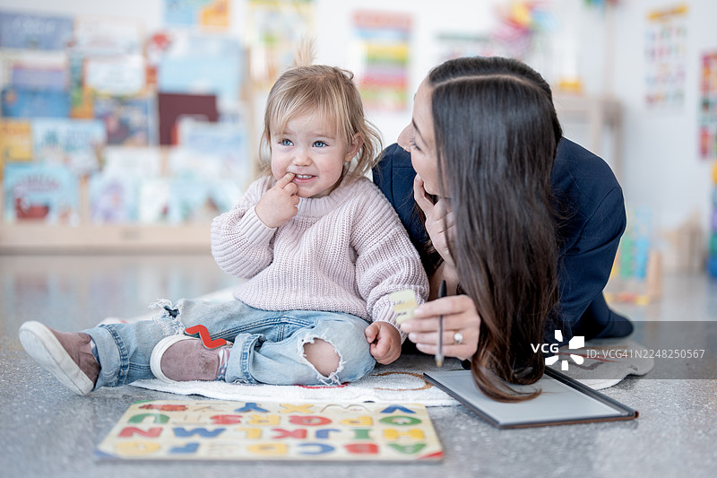 明亮的教室里，母亲和年幼的女儿一起学习和玩耍图片素材