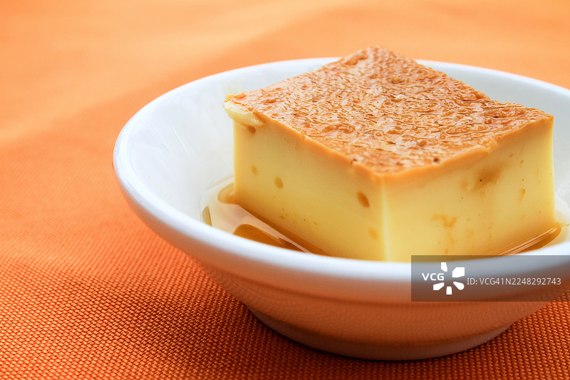 橙色背景上的立方体焦糖布丁图片素材