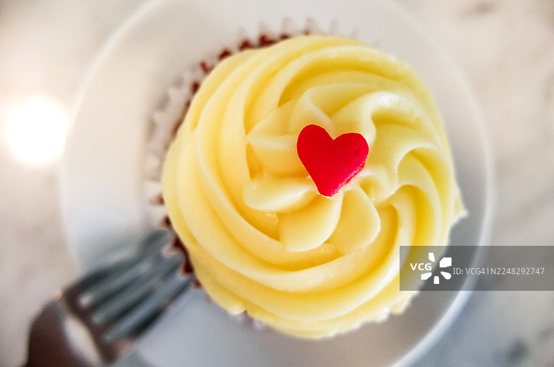 香草蛋白霜杯子蛋糕，顶部覆盖着一层心形的草莓果酱图片素材