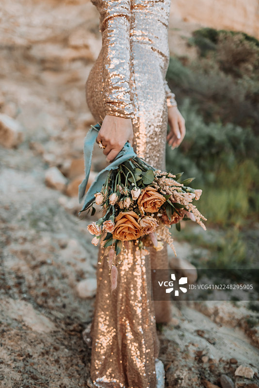 身穿金色亮片连衣裙的女子手持乡村风格花束的特写图片素材