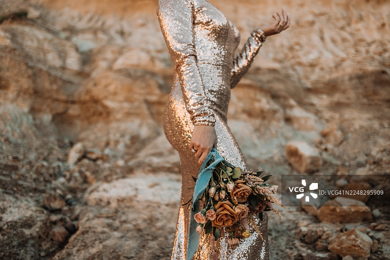 金色亮片连衣裙女子手持乡村风花束的特写图片素材