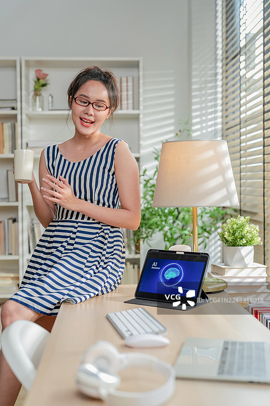 女性手部特写，在智能手机和平板电脑上与人工智能驱动的虚拟代理互动，显示屏上展示智能技术，在家中通过无缝的数字智能管理任务图片素材