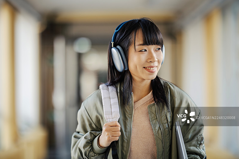 戴着耳机走在走廊里的女学生图片素材