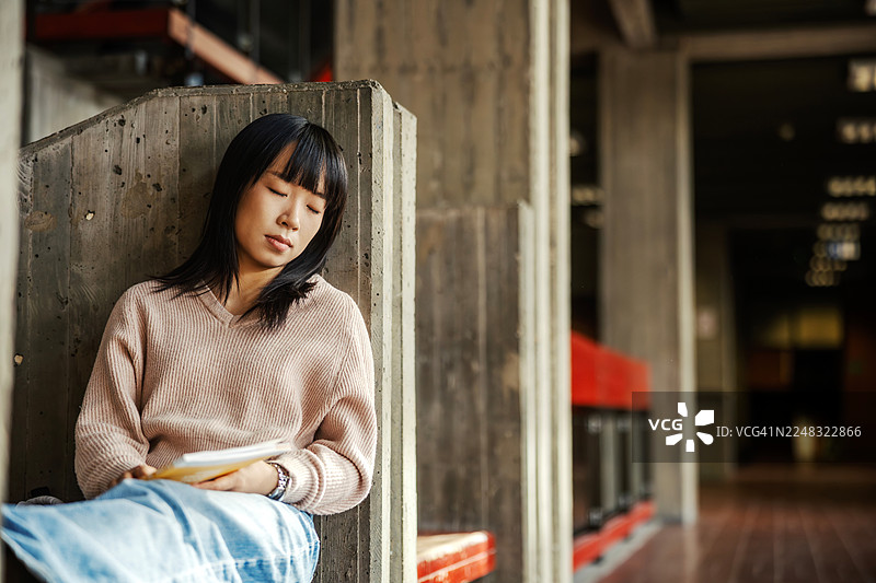 年轻的亚洲女子在学习后睡在水泥长凳上图片素材