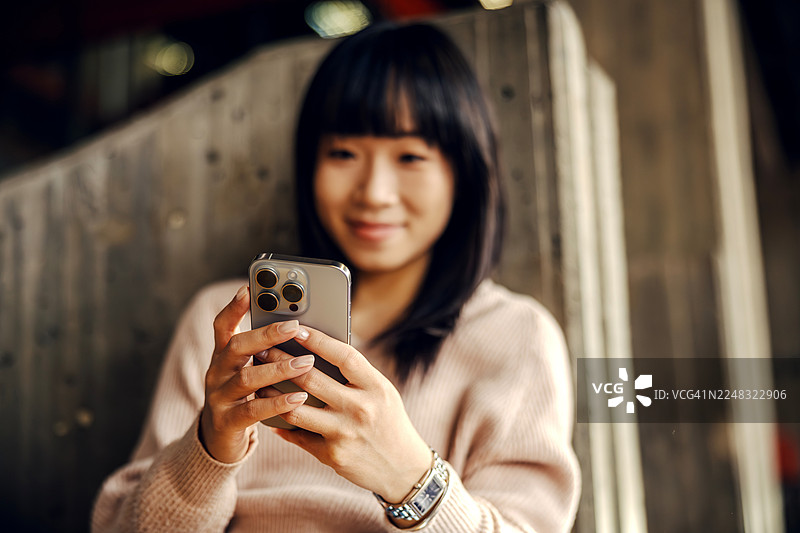 年轻的亚洲女性，手持手机，面带微笑图片素材