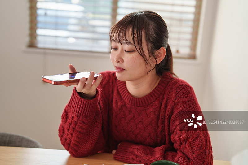 女性在家中使用语音助手获取远程健康支持图片素材