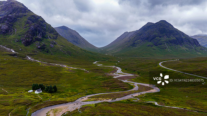 苏格兰高地格伦科山谷，考帕尔河畔的拉甘加布小屋的鸟瞰图，背景是壮丽的山脉和多云的天空，标志性的旅行和荒野景观概念图片素材