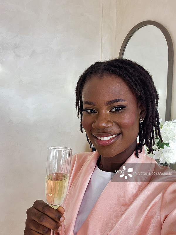 年轻的黑人女性在美容院化完妆后，一边喝香槟一边自拍图片素材