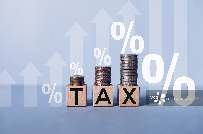木块上刻有“税务”字样，旁边堆叠着硬币，税务概念图片素材