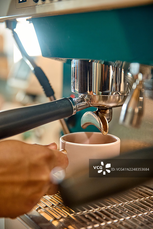 特写镜头，一台绿色咖啡机正在向杯中注入咖啡。图片素材