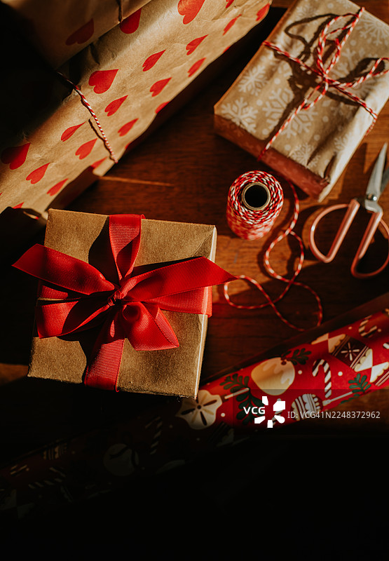 圣诞节礼品包装场景。礼物旁放着红白两色麻绳和剪刀。图片素材