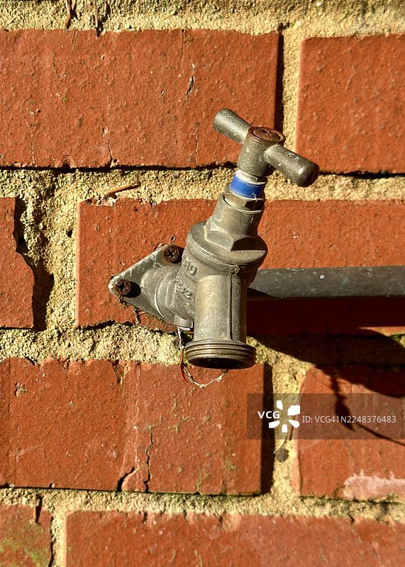 砖砌建筑外老旧破损的水龙头和管道图片素材