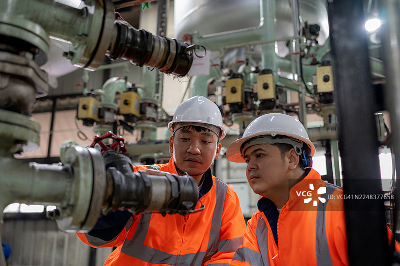 技术人员在化工厂工作场所检查管道设备零件和仪表，并解释有助于防止故障和加强全球业务运营的维护计划，炼油厂生产线图片素材