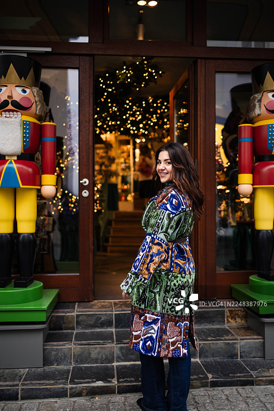 圣诞集市上，一位女士站在两个胡桃夹子士兵之间，面带微笑图片素材