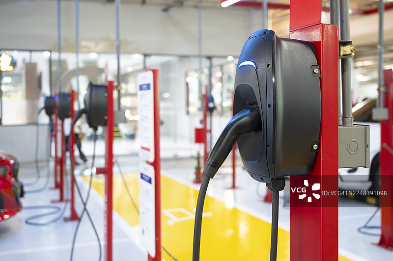 电动汽车充电站插头连接到电动汽车。电动汽车充电站插头连接器能源可再生能源可持续技术汽车交通清洁环境基础设施未来模糊背景。图片素材