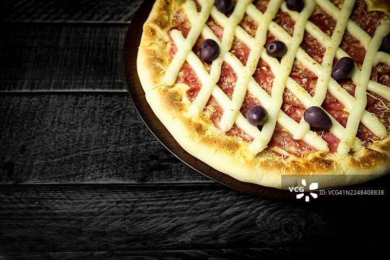 深色背景下的披萨，配有木桌和香料。图片素材