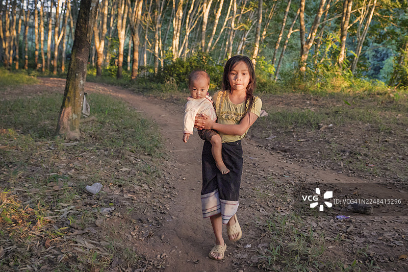 老挝北部偏远村庄里，老挝小女孩抱着一名婴儿图片素材
