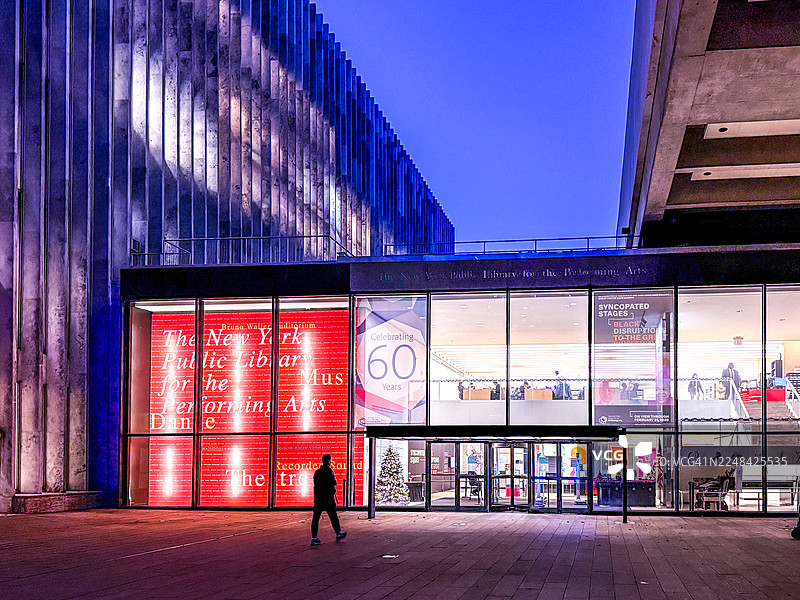 纽约林肯中心表演艺术图书馆外，一名男子在黄昏时行走图片素材
