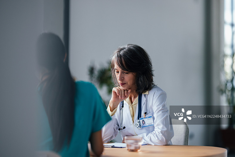 医生在安静的医院办公室场景中咨询病人，充满关怀的医疗互动图片素材