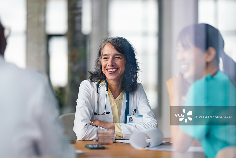 身穿白大褂的医生在明亮的医院会议室里与患者讨论健康问题图片素材