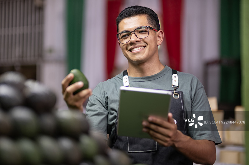 牛油果销售商打理生意并检查产品质量图片素材