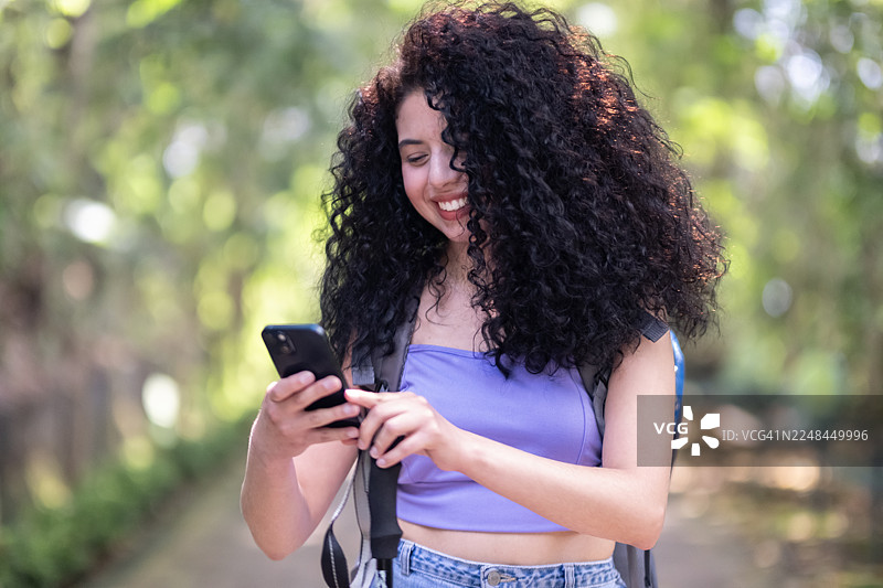 年轻女子背着背包、拄着登山杖在自然环境中徒步图片素材