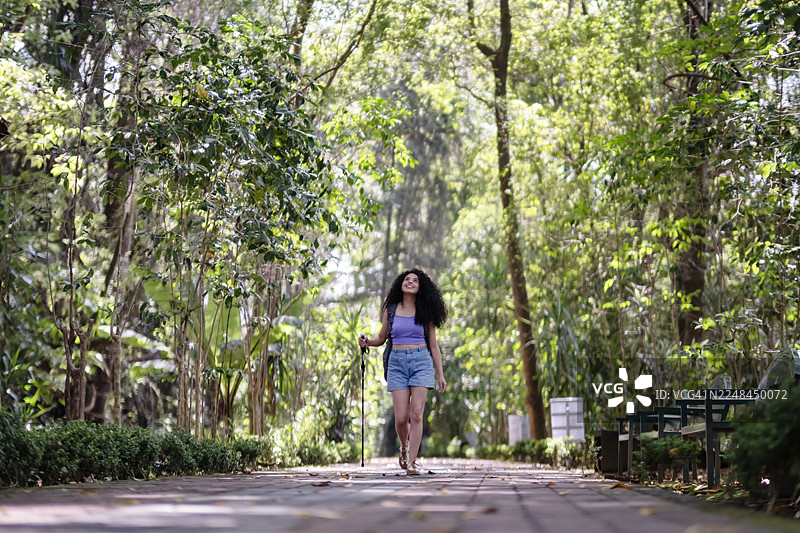 背着背包、拄着登山杖的年轻女子在自然环境中徒步图片素材