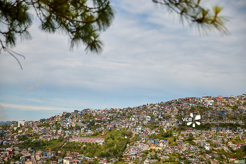多云天空下的密集山坡城镇。图片素材