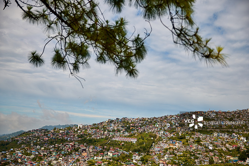 阴云密布的天空下，山坡上人口稠密的城镇。图片素材