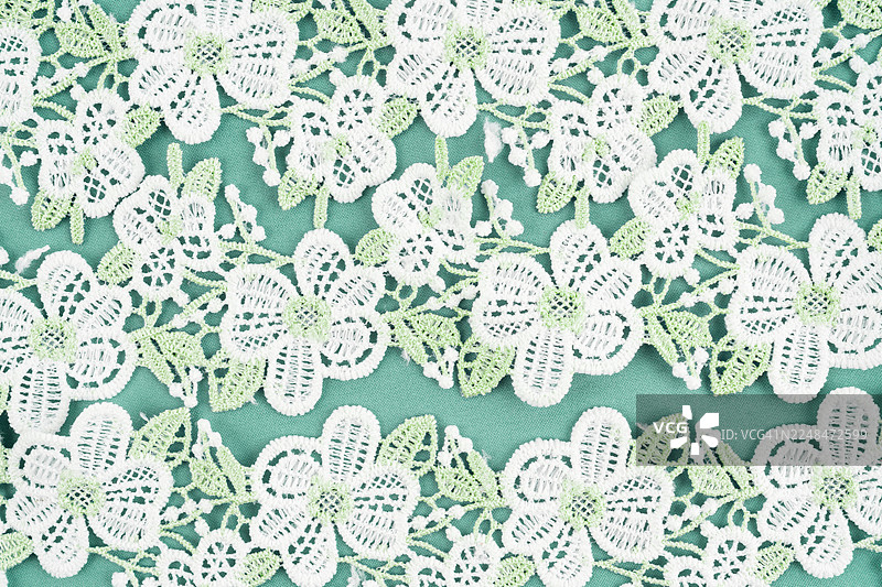 绿色织物背景上的花卉和绿叶蕾丝纺织品图案图片素材