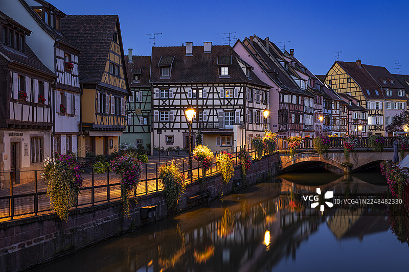 夏日傍晚的蓝色时刻，拍摄了阿尔萨斯村庄科尔马的著名运河。美丽的阿尔萨斯风格房屋倒映在水中。法国，阿尔萨斯，科尔马，欧洲图片素材