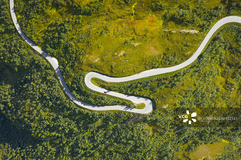 从空中俯瞰，蜿蜒的道路穿过崎岖的地形，岩石上点缀着零星的绿色植被，地点是挪威摩尔和罗姆斯达尔的盖朗厄尔。图片素材