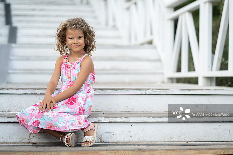 穿着夏日连衣裙的年轻女孩在户外微笑图片素材