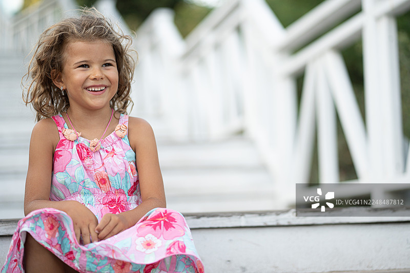 穿着夏日连衣裙的年轻女孩在户外微笑图片素材