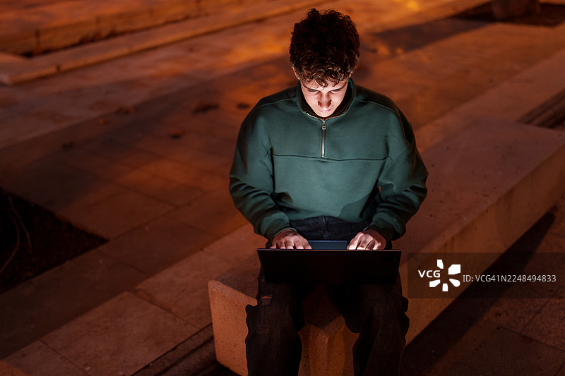 少年在户外深夜使用笔记本电脑工作图片素材