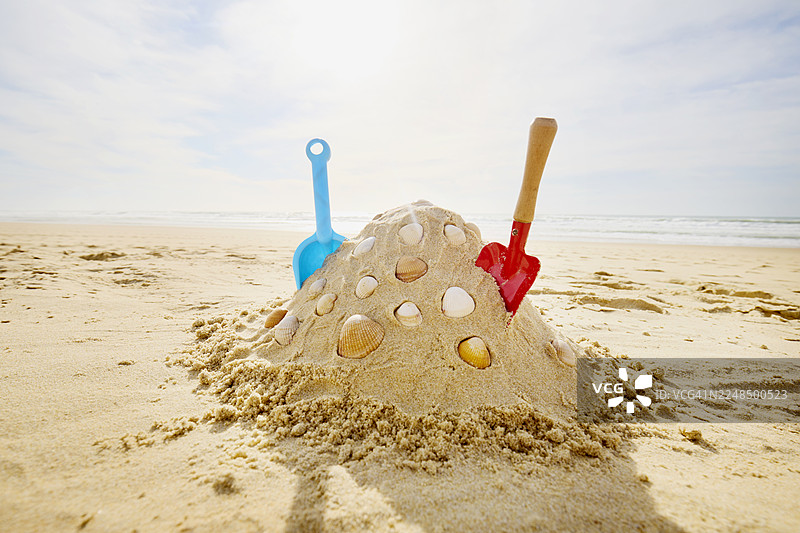 沙滩上用红蓝铲子建造的沙堡，背景是大海和天空图片素材