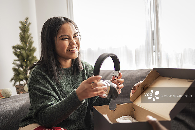 快乐的女士在节日期间拆开礼品耳机图片素材