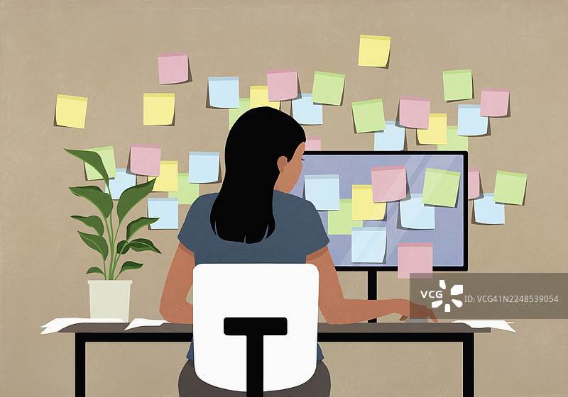 女商人在办公桌前工作，电脑和墙上贴满了便利贴图片素材