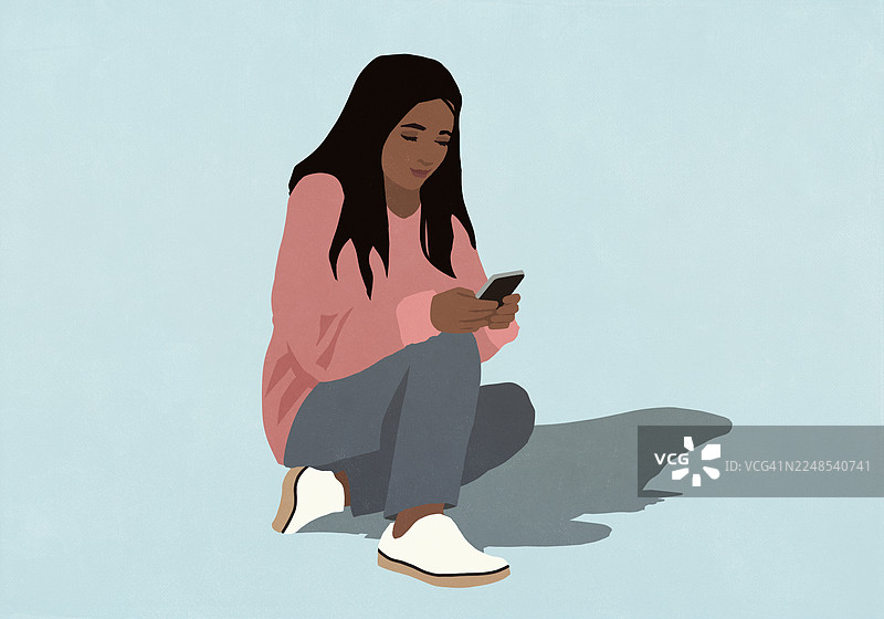 一个女人坐在蓝色的背景前，正在使用智能手机图片素材