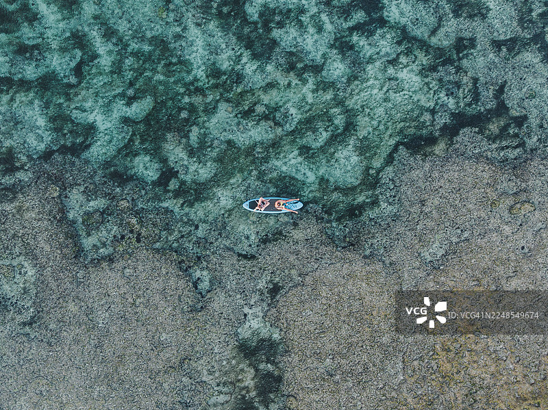无人机视角下的印度洋，巴厘岛乌鲁瓦图，一对情侣在珊瑚礁旁划皮划艇图片素材