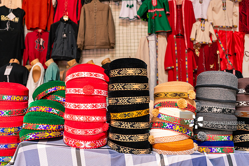 一堆色彩鲜艳的传统小圆帽在集市摊位上展示着精美的图案和丰富的色彩，提供手工制作的当地文化和纪念品出售图片素材