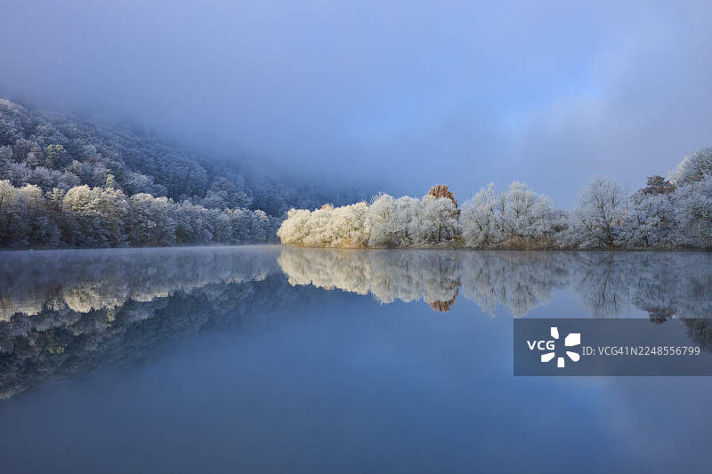 宁静的河流倒映着冬日严寒中的霜冻树木和山脉,有霜花,冬季,博克斯塔尔,美因-陶伯县,巴登-符腾堡州,以及施塔特普罗策尔滕,多夫普罗策尔滕,美因河,斯佩萨特,巴伐利亚州,德国图片素材